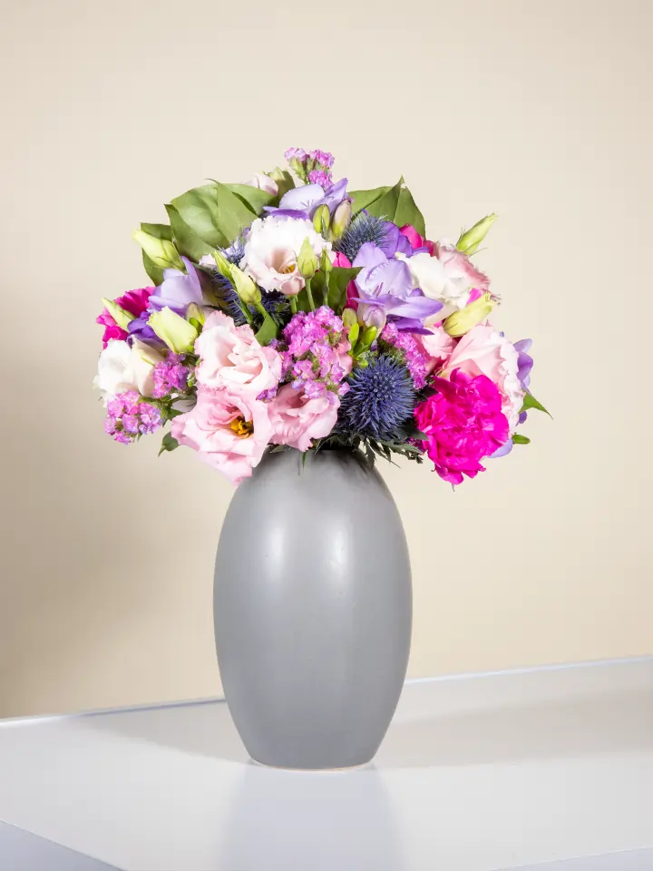 Bouquet viola lilla con lisianthus eryngium garofani in vaso grigio